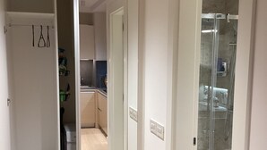 Un pasillo con cocina, cabina de ducha de vidrio y armario.