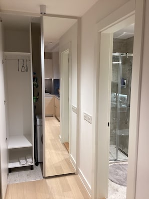 En gang med et tekøkken, en glasbrusekabine og et klædeskab.
