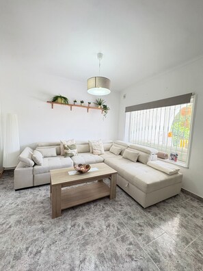 A modern living room with a sectional sofa, a wooden coffee table, and a large window with a view. - Townhouse in a quiet neighborhood (El Chaparral)
