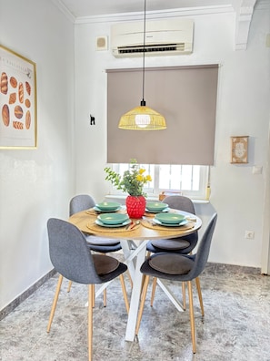 A dining area with a round table, four chairs, a hanging pendant light, and a window with a view. - Townhouse in a quiet neighborhood (El Chaparral)