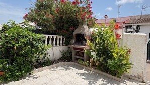 A patio area with a tiled floor, a stone wall, and a variety of plants including a flowering bush. - Townhouse in a quiet neighborhood (El Chaparral)