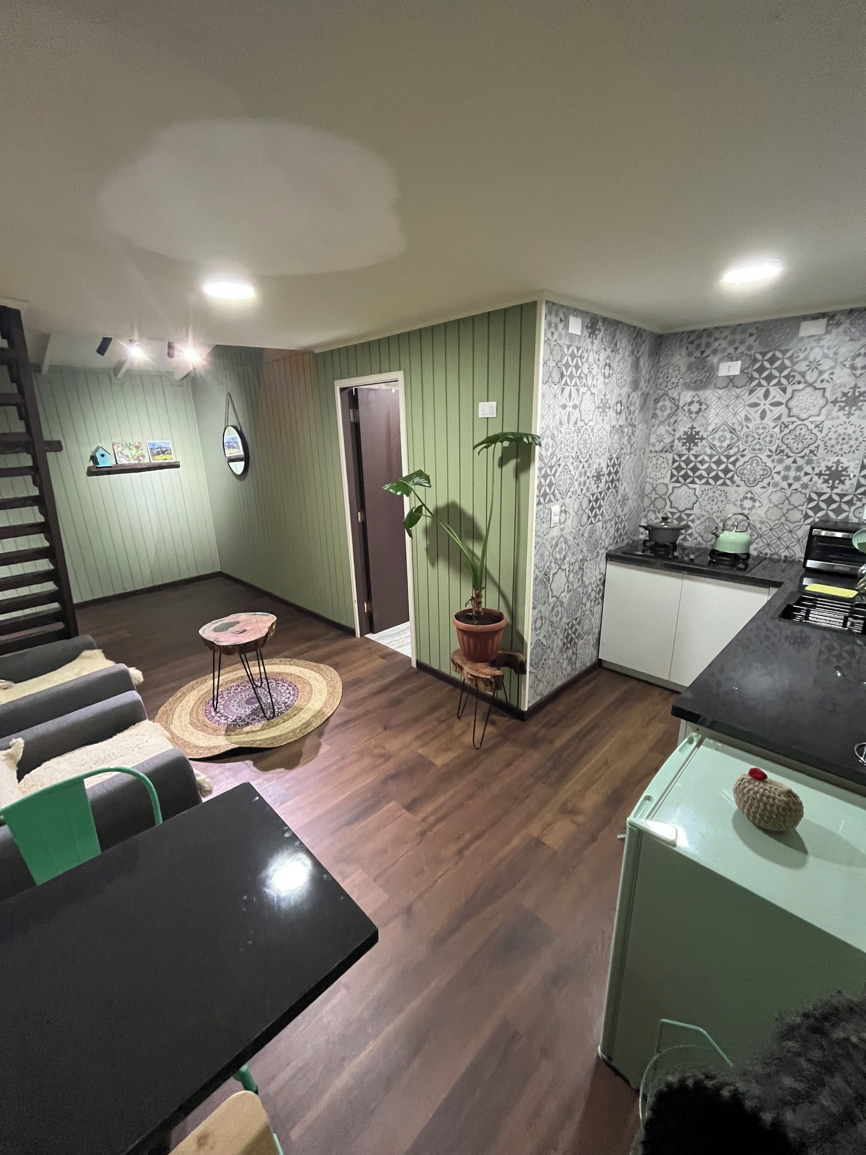 Una sala de estar con comedor, cocina y escalera.