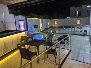 A rooftop terrace with a glass balustrade, outdoor seating, and a pool area. - Taperapuã Beach - Ashby Houses (Porto Seguro)