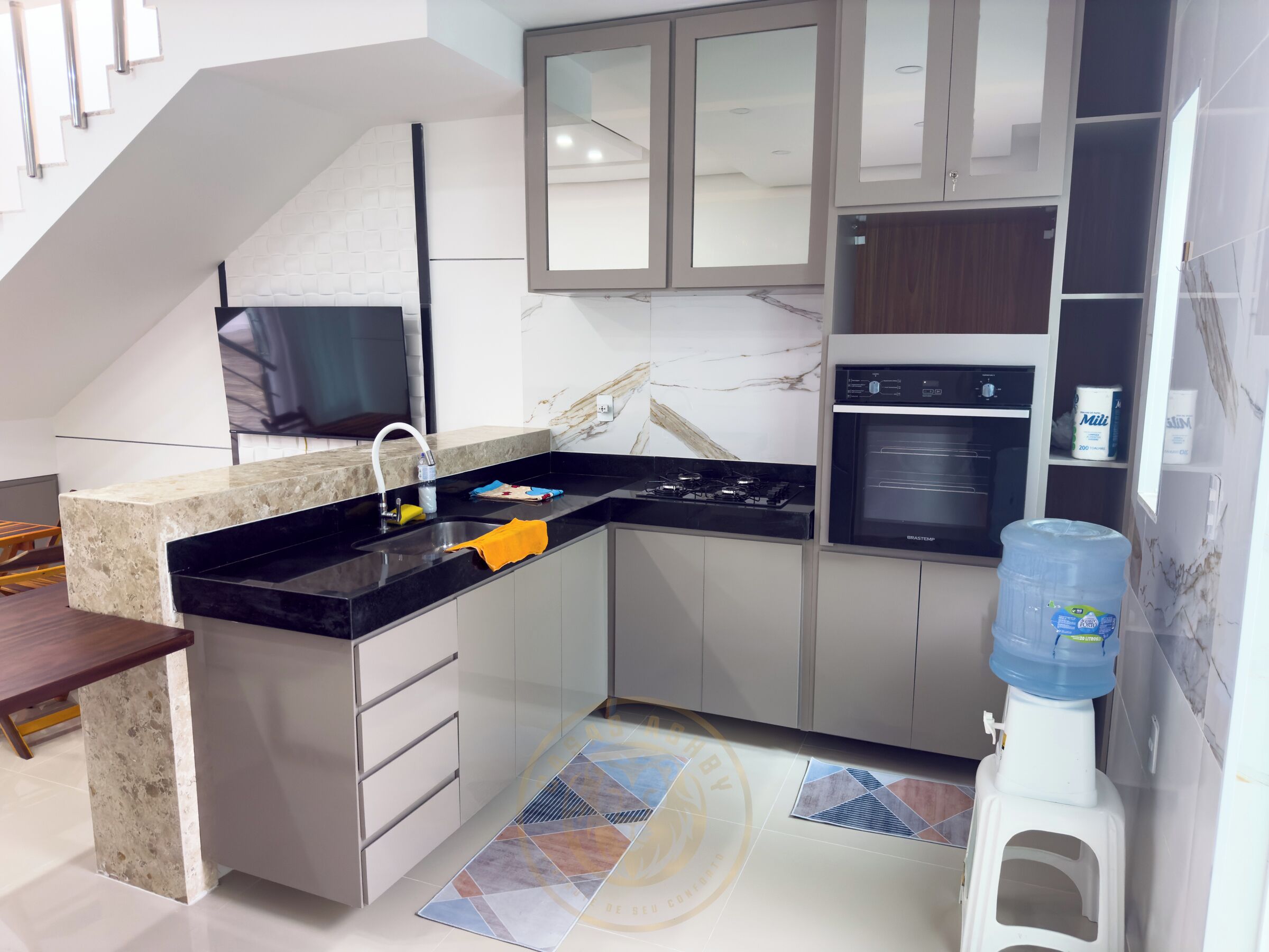 Eine moderne Küche mit Backofen, Wasserspender und Spüle.