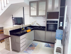 A modern kitchen with a built-in oven, a water dispenser, and a sink. - Taperapuã Beach - Ashby Houses (Porto Seguro)