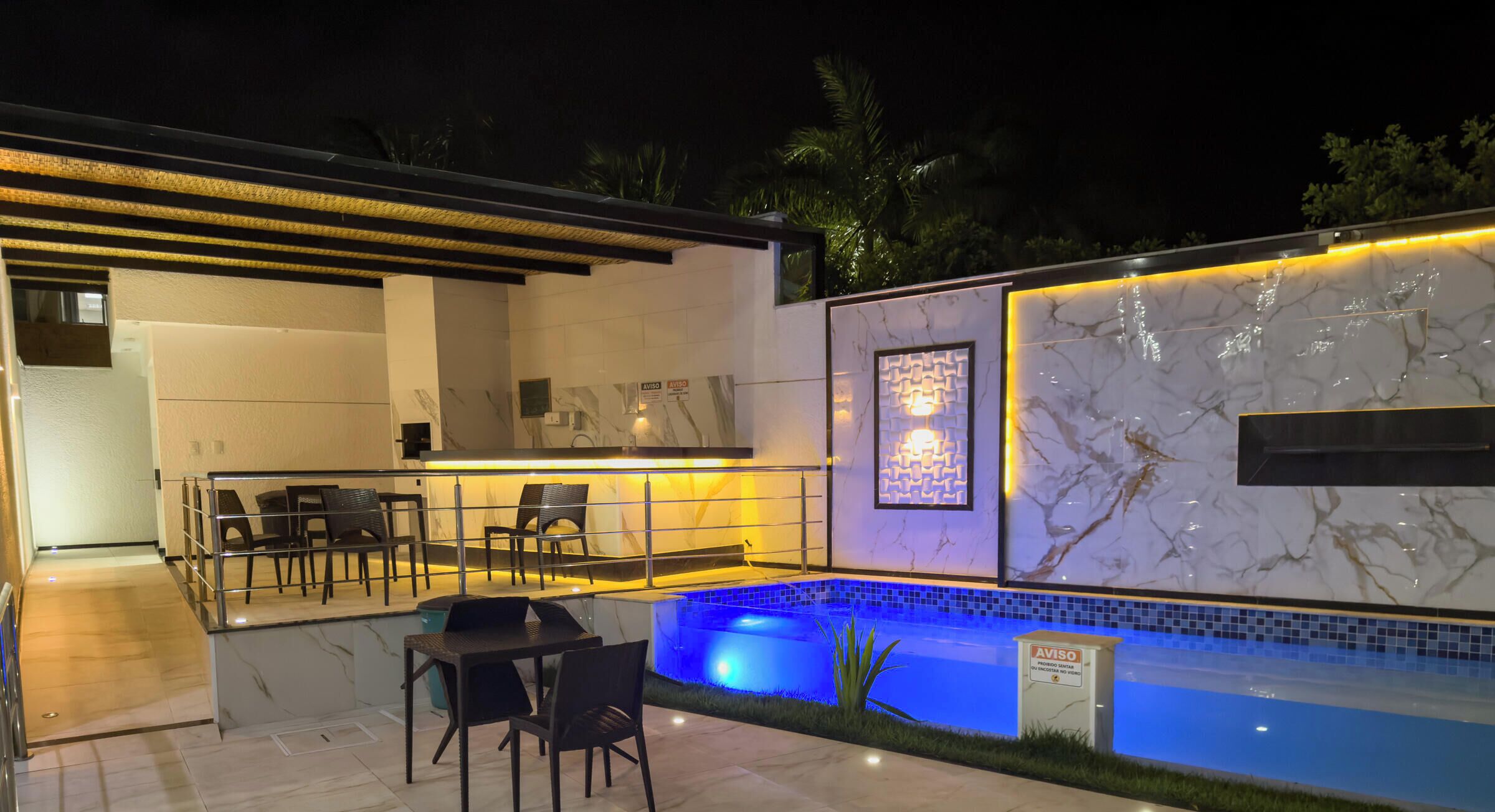 En utomhusveranda med pool, sittgrupp och en modern arkitektonisk design.