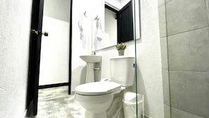 A bathroom with a toilet, sink, and mirror. - Jardin Loft (Medellín)