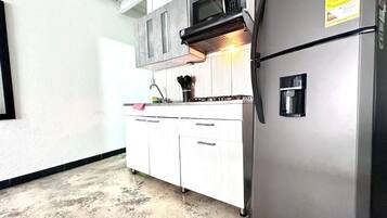 A kitchen with white cabinets, a stainless steel refrigerator, a microwave, and a gas stove.