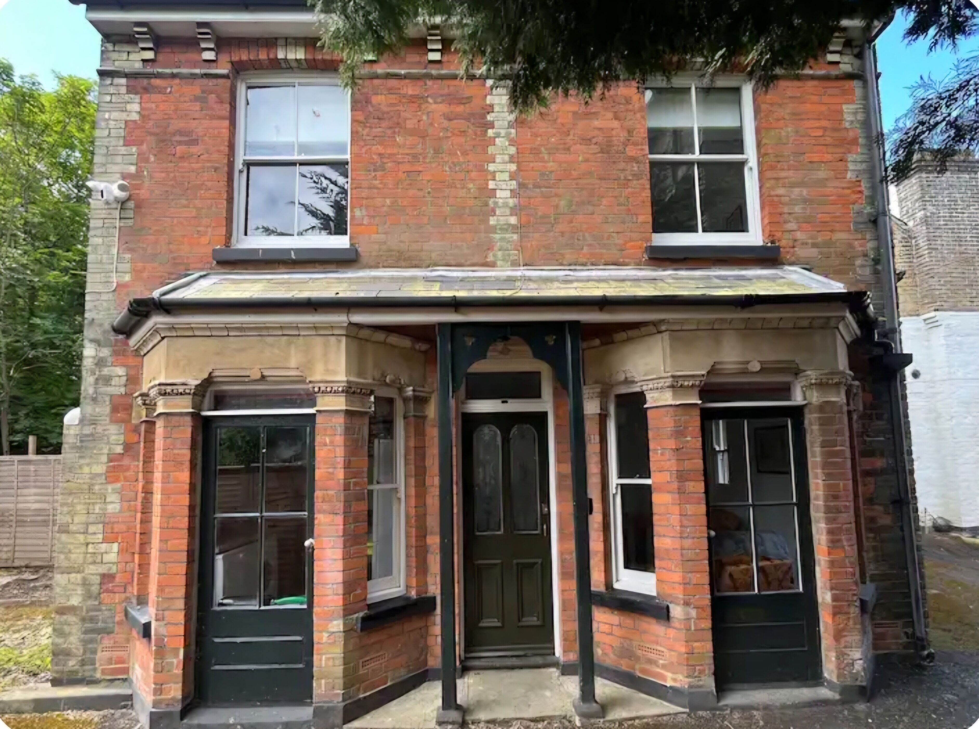 A corner building with a bay window, a front door, and a small porch area.