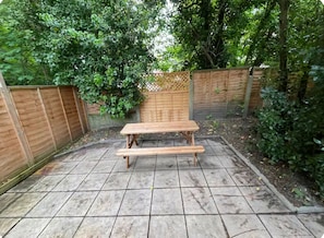 A wooden bench in a garden area with a tiled floor and a wooden fence. - St Mary's Cottage One
Entire 2 bedroom cottage - a home from home (Dover)
