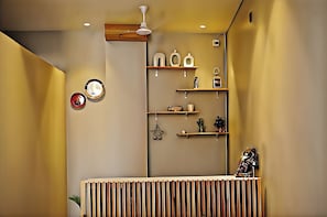 A room with a wooden slatted desk, wall-mounted shelves with various items, and a ceiling fan. - The homez haven (Rishikesh)