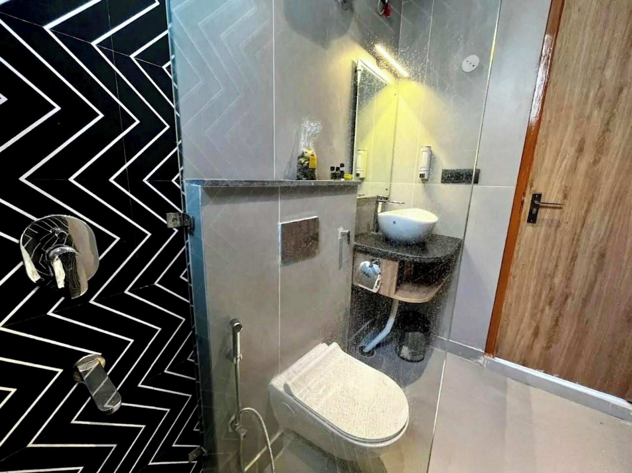 A modern bathroom with a glass shower enclosure, a white sink, and a mirror above it.