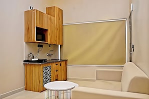 A compact living space with a kitchenette, a sofa, and a small round table. - The homez haven (Rishikesh)