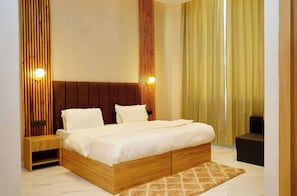 A bedroom with a wooden bed frame, a nightstand, a patterned rug, and a curtain. - The homez haven (Rishikesh)