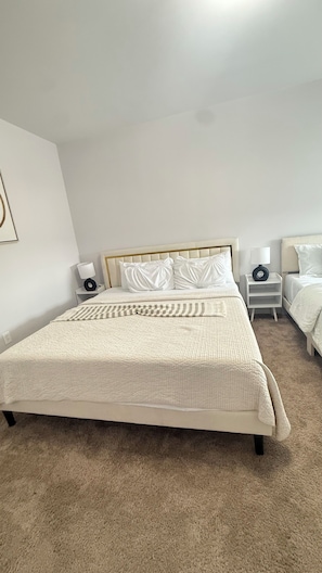 Ein Schlafzimmer mit einem großen Bett, zwei Nachttischen, einem Beistelltisch und einer Wandlampe.