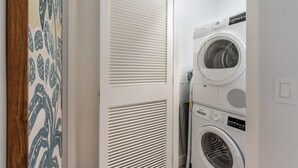 A laundry room with stacked washing machines and dryers. - Luxury 1BR Residence at One GT · Rooftop Pool & Views (George Town)
