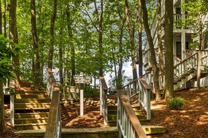 A wooden staircase surrounded by trees leading to a building with a balcony. - Loggers Lookout Condo at The Homestead (Glen Arbor)