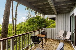 A wooden deck with a railing, two chairs, and a table. - Loggers Lookout Condo at The Homestead (Glen Arbor)