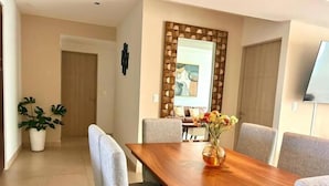 Ein stilvoller Essbereich mit einem Holztisch, grauen Polsterstühlen und einer Blumenvase.