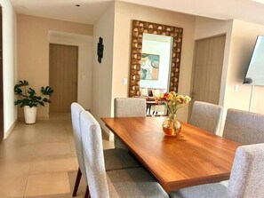 Un espace repas moderne avec une table en bois, des chaises à revêtement gris et un vase de fleurs.