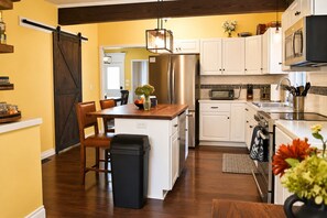 A kitchen with a central island, white cabinets, stainless steel appliances, and a wooden floor.