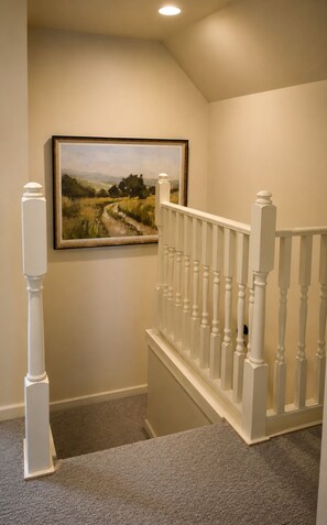 Un escalier avec des balustrades blanches et une plateforme recouverte de moquette.
