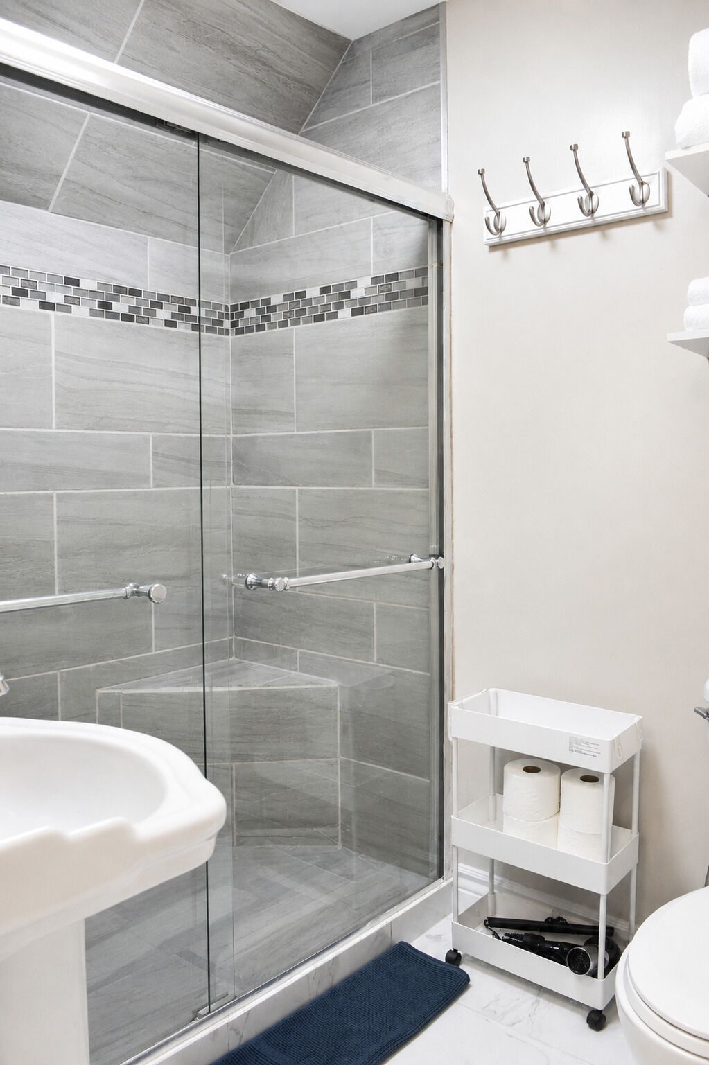 A modern bathroom with a glass-enclosed shower, a white sink, and a white toilet.