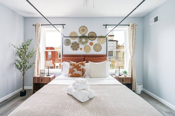 Une chambre d’hôtel avec un lit, une œuvre d’art accrochée au mur, une plante en pot et une vue sur l’extérieur.