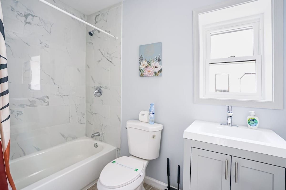 A bathroom with a bathtub, toilet, and a sink with a mirror above.