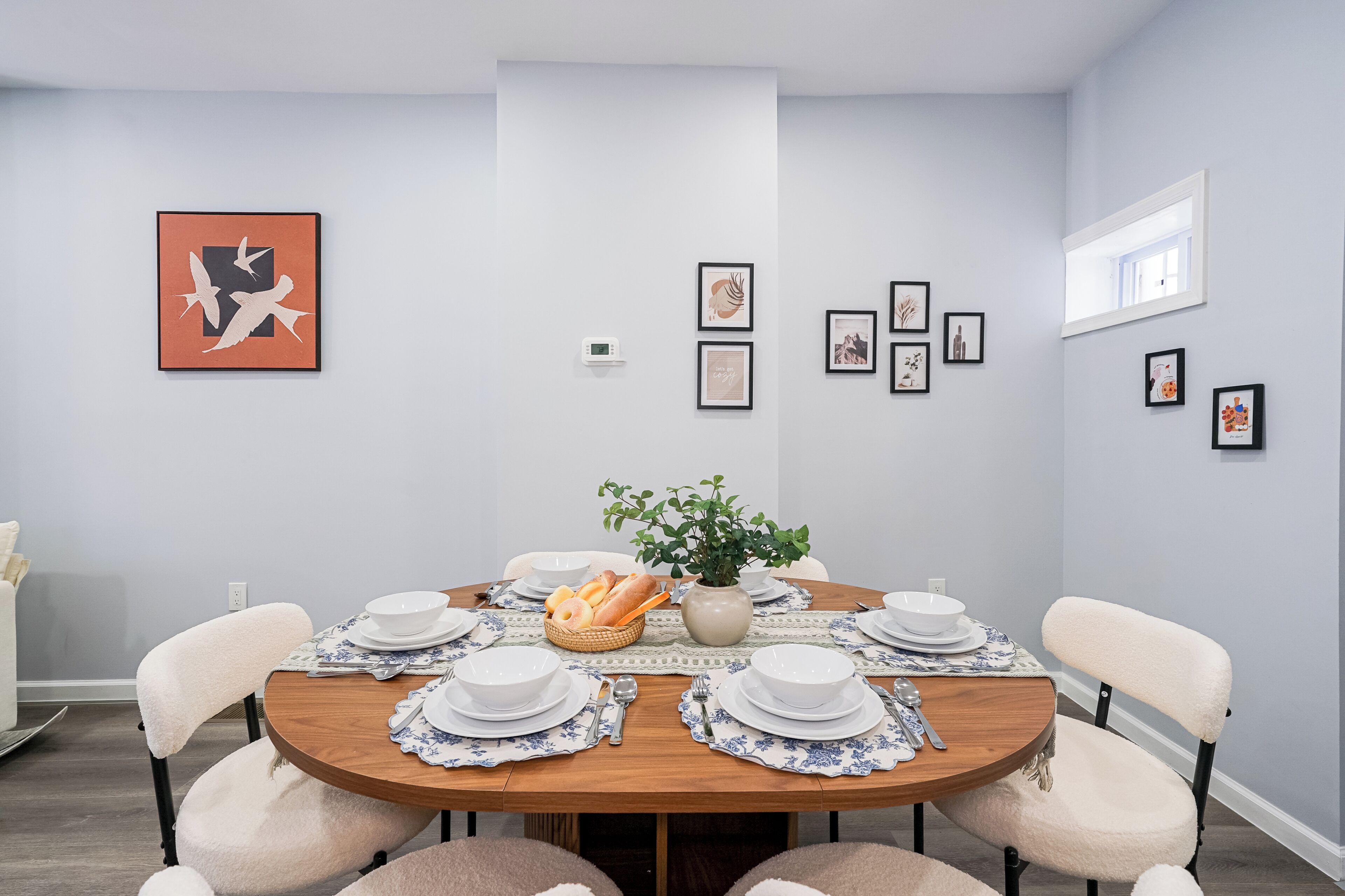 Ein Esszimmer mit einem runden Tisch, gedeckt für vier Personen, umgeben von Stühlen.