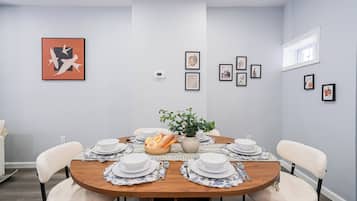 Ein Esszimmer mit einem runden Tisch, gedeckt für vier Personen, umgeben von Stühlen.