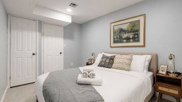 A bedroom with a large bed, two nightstands, a framed picture on the wall, and a door.