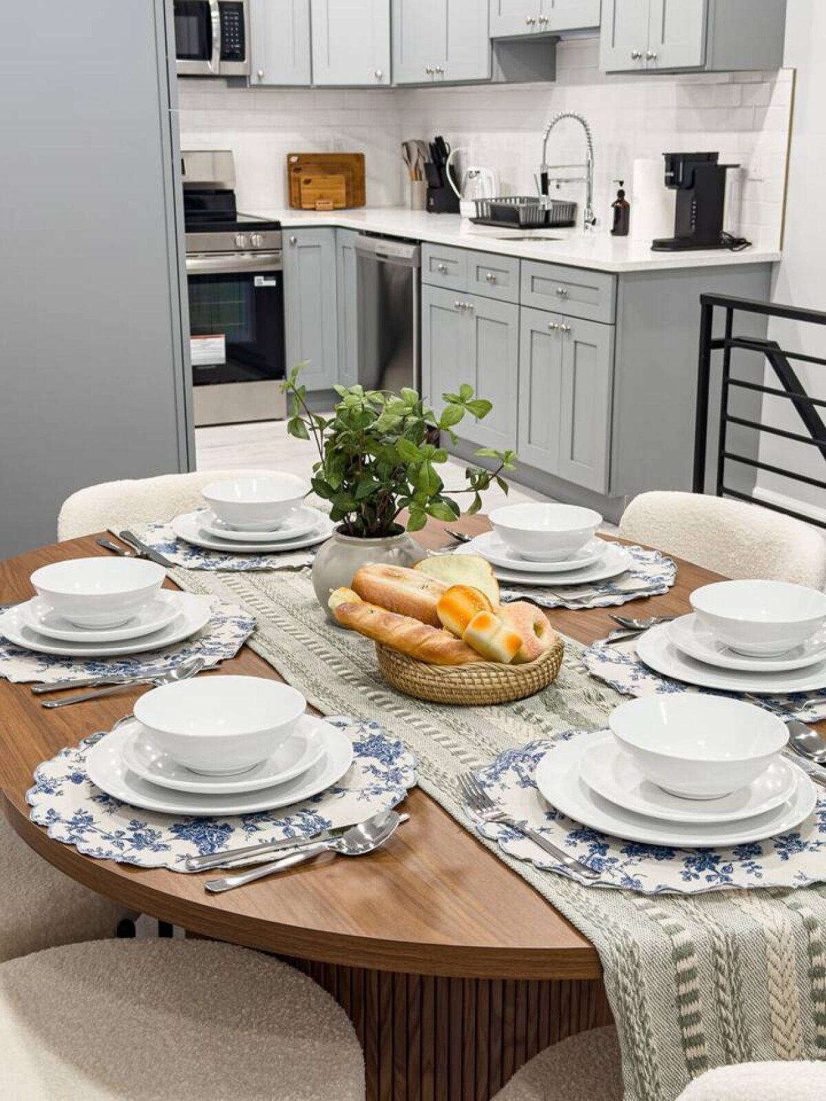 A dining area with a round table set for six, surrounded by chairs.