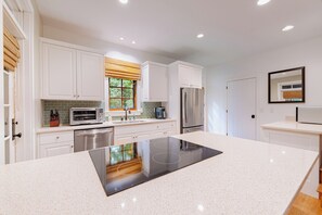 A modern kitchen with white cabinetry, a built-in stove, and a stainless steel refrigerator. - Cashiers 3-bedroom home in Trillium (Cashiers)