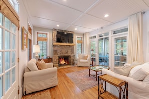 A spacious living room with a stone fireplace, comfortable seating, and large windows. - Cashiers 3-bedroom home in Trillium (Cashiers)
