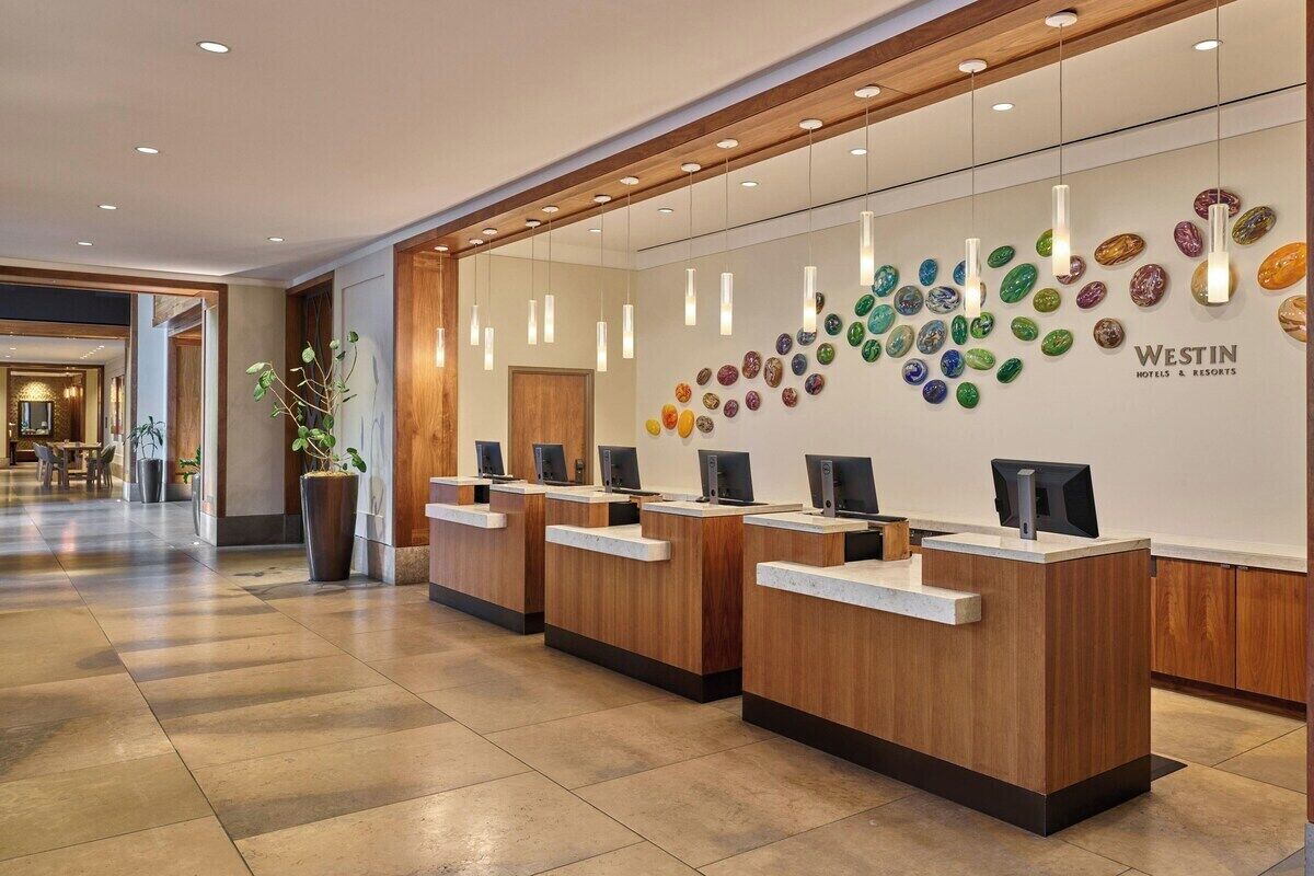 Un'area reception con scrivanie in legno, una parete di pietre colorate e un cartello per Westin Hotels & Resorts.