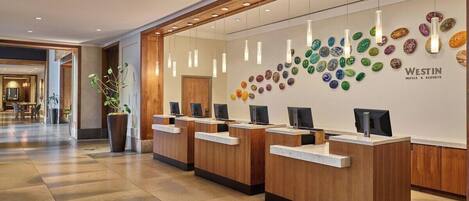 A reception area with wooden reception desks, a wall of colorful stones, and a sign for Westin Hotels & Resorts.