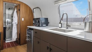 Cocina compacta con lavavajillas integrado, un lavamanos con grifo moderno y ventana con vistas al exterior.