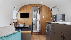 Una kitchenette compacta con una televisión de pantalla plana, un microondas y un lavamanos.
