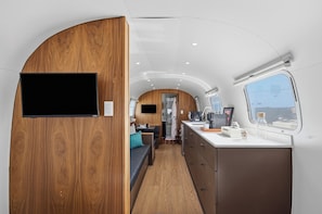 Un interior compacto con una pared de madera decorativa, una kitchenette y una zona de estar.