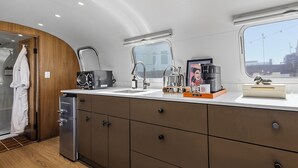 A compact kitchen with a built-in dishwasher, a sink with a modern faucet, and a window providing a view of the outside. - Private Airstream on a Hidden Courtyard Near Downtown (Fort Worth)