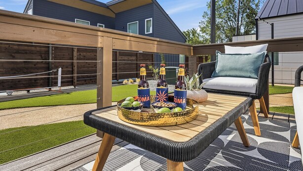 A patio area with a wicker table, a wicker chair, and a wooden pergola. - Private Airstream on a Hidden Courtyard Near Downtown (Fort Worth)