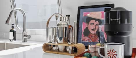 A kitchen counter with a coffee maker, a framed artwork, and a mug.