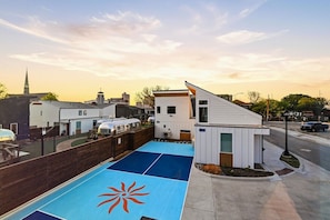 A modern building with a sloped roof, a small attached structure, and a blue outdoor area with a sun-like design. - King casita on the garden courtyard, near downtown (Fort Worth)
