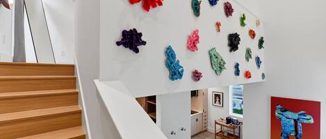 Una escalera con barandilla blanca que lleva a una habitación con pared blanca y piso de madera.