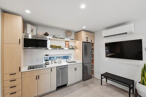 A modern kitchen with stainless steel appliances, a built-in microwave, and a flat-screen TV mounted on the wall. - King casita on the garden courtyard, near downtown (Fort Worth)
