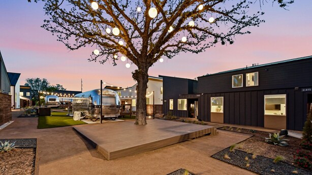 Un espace extérieur moderne agrémenté d’un arbre, d’un barbecue et d’une terrasse en bois.
