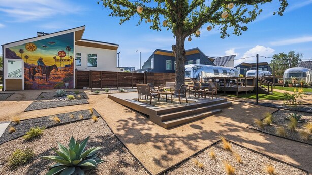 Un hotel moderno con un murale, posti a sedere all'aperto e camper.