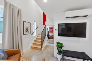 Ein modernes Interieur mit Treppe, Flachbildfernseher, Topfpflanze und einer Bank.