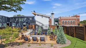 Ein modernes Wohnhaus mit einer Terrasse, Sitzgelegenheiten im Freien und einem gepflegten Garten.